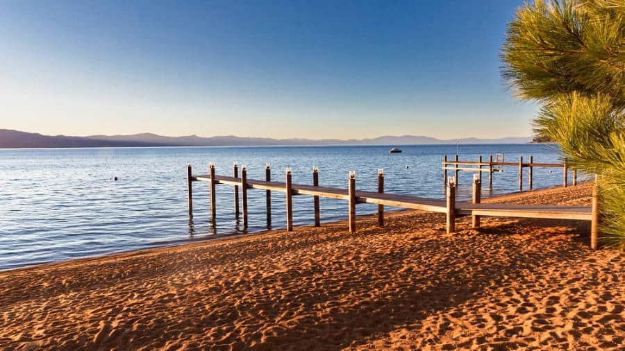 View of the boardwalk extending on a sandy beach in Lake Tahoe during sunset