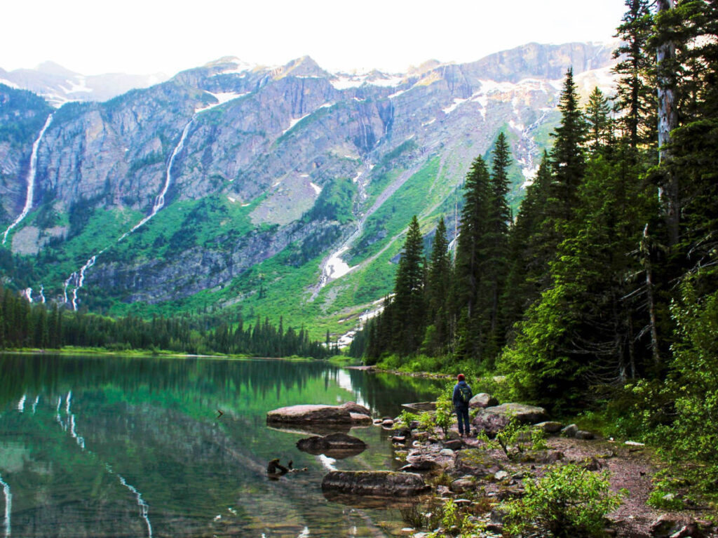A hiker admiring the scenic view of the lake and the landscape in Glacier National Park