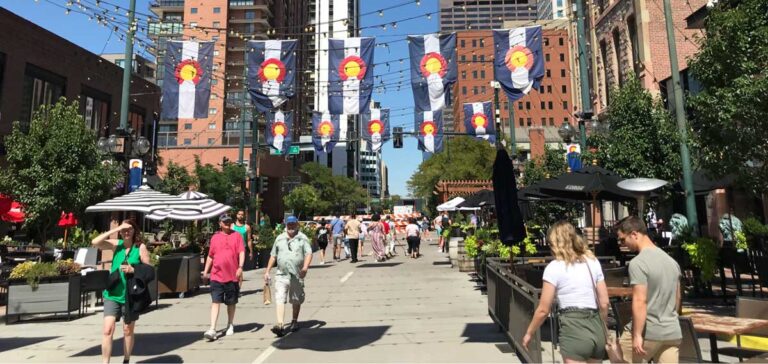 People walking under Colorado flags in Larimer Square in Denver