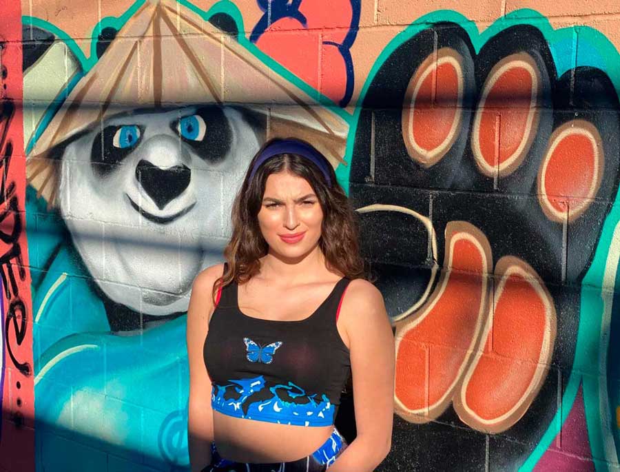 The author posing for a photo with a mural in Las Vegas Arts District on her background
