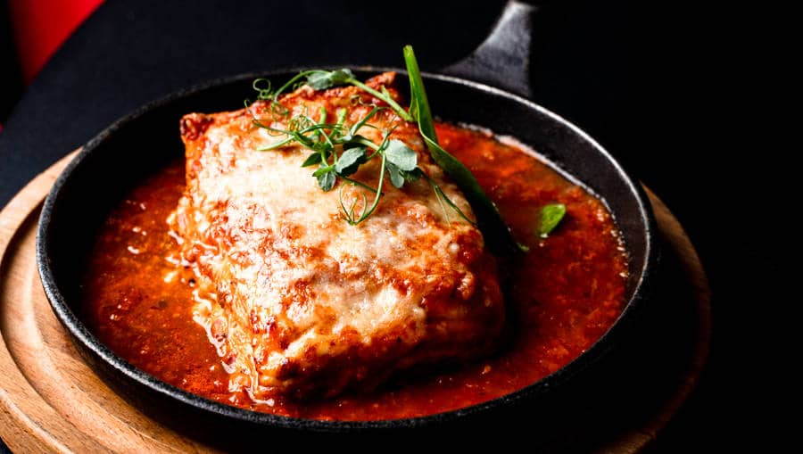 A pan with sliced classic lasagna with tomato sauce