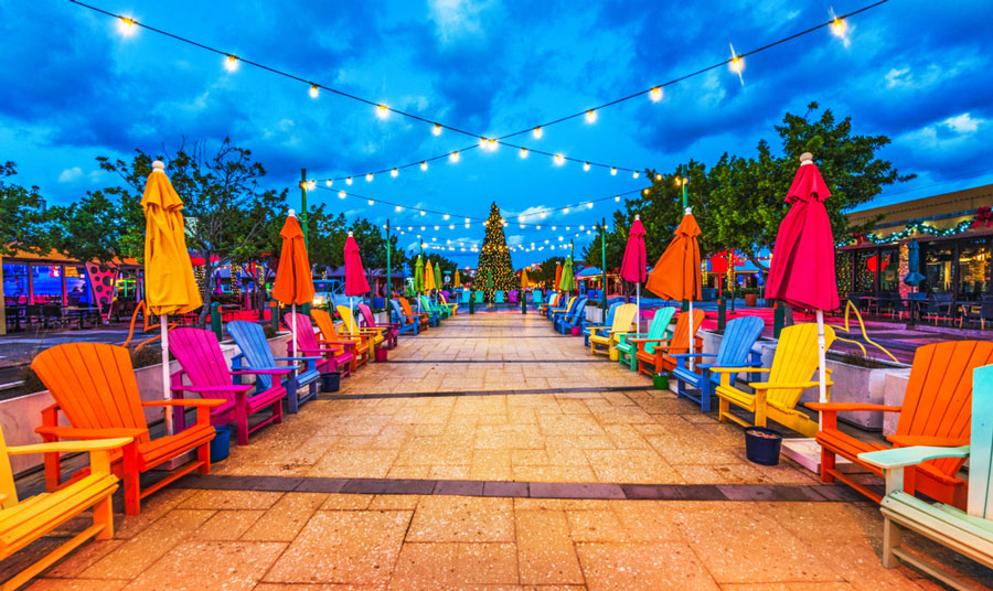 View of a walkway in a beachfront town center and colorful seats and umbrellas along it