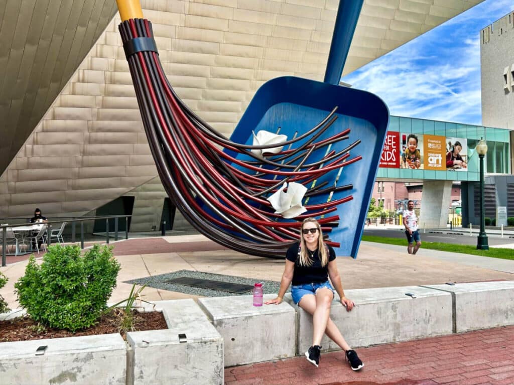 The author Laura Falin, sitting outside The Denver Art Museum with the iconic sculpture in the background