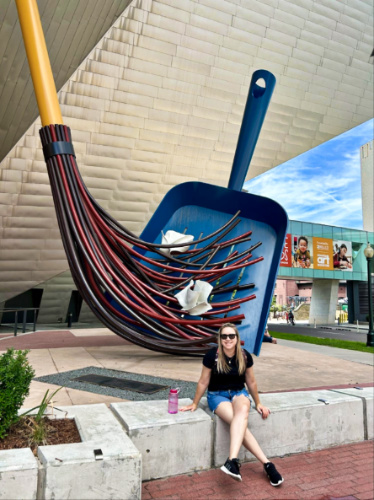 The author Laura Falin, sitting outside The Denver Art Museum with the iconic sculpture in the background