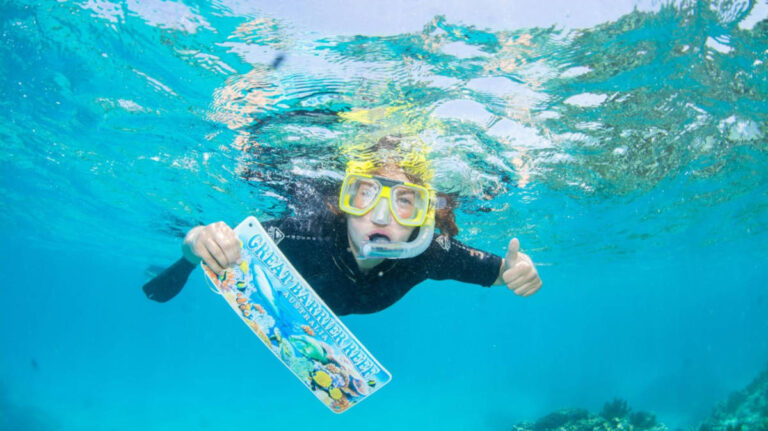 The author Laura McFarland holding a signage while snorkeling on the Great Barrier Reef