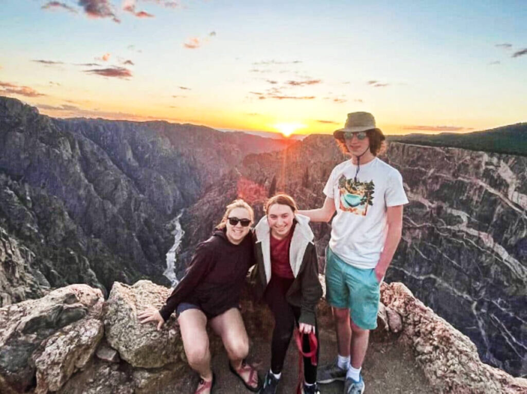 The author Laura Falin with her son and daughter, posing for a photo at Black Canyon of the Gunnison National Park at sunset