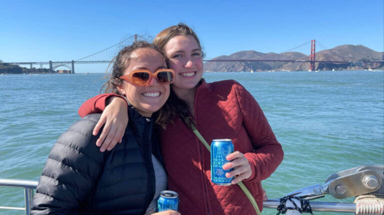 The author Laura and her partner holding their can of beer with the Golden Gate Bridge behind