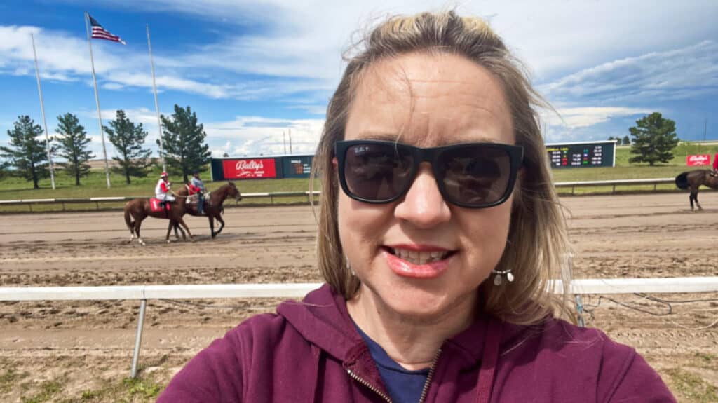 The author, Laura Falin taking a photo of herself at the Bally’s Arapahoe Park with an ongoing horse race in the background