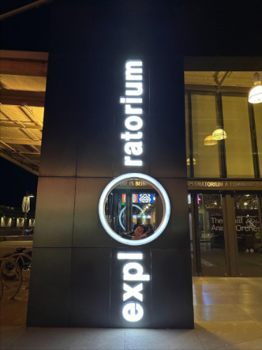 The author, Laura McFarland smiling for a photo in The Exploratorium sign