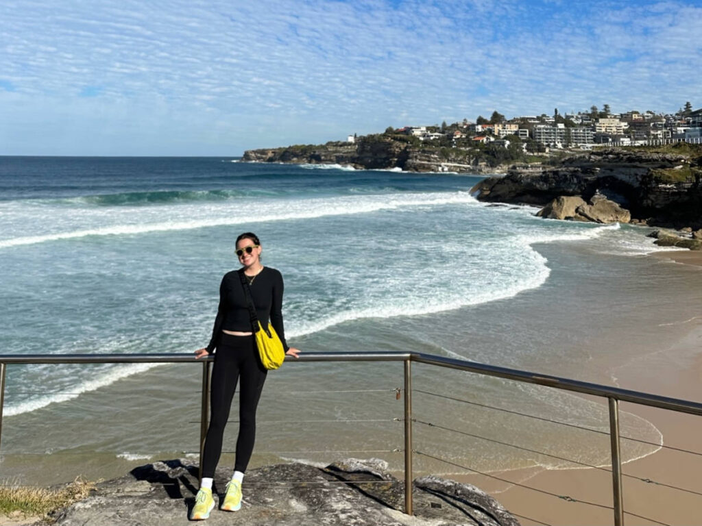The author Laura McFarland posing for a photo with an overlooking view of the Coogee Coastal Walk