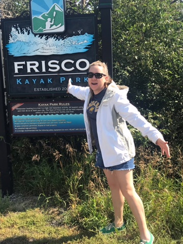 Laura Falin in front of the Frisco Kayak Park sign