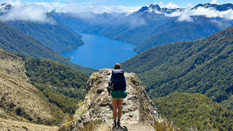 The author Laura McFarland standing on the hill with her backpack overlooking the lake