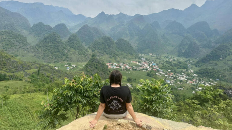 The author Laura McFarland posing for a photo with the scenic view on the Ha Giang Loop Viewpoint