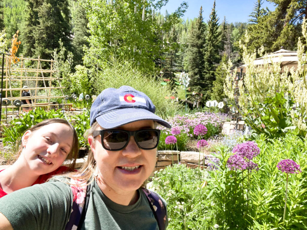 Thea author Laura Falin and her child smiling for a photo at the beautiful landscape of Children’s Garden