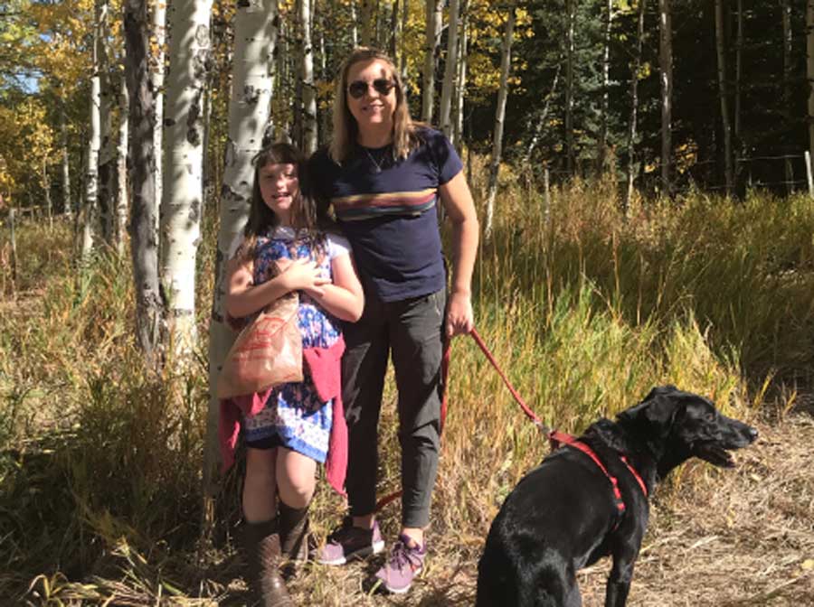 The author holding a dog leash with her daughter during a hike