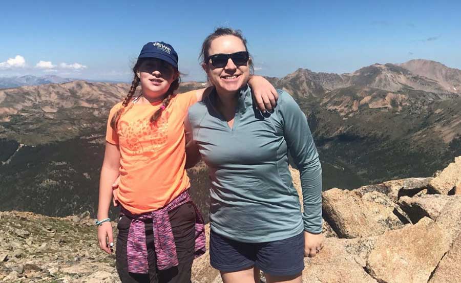 The author with her daughter smiling for a photo with the view from the Loveland Pass