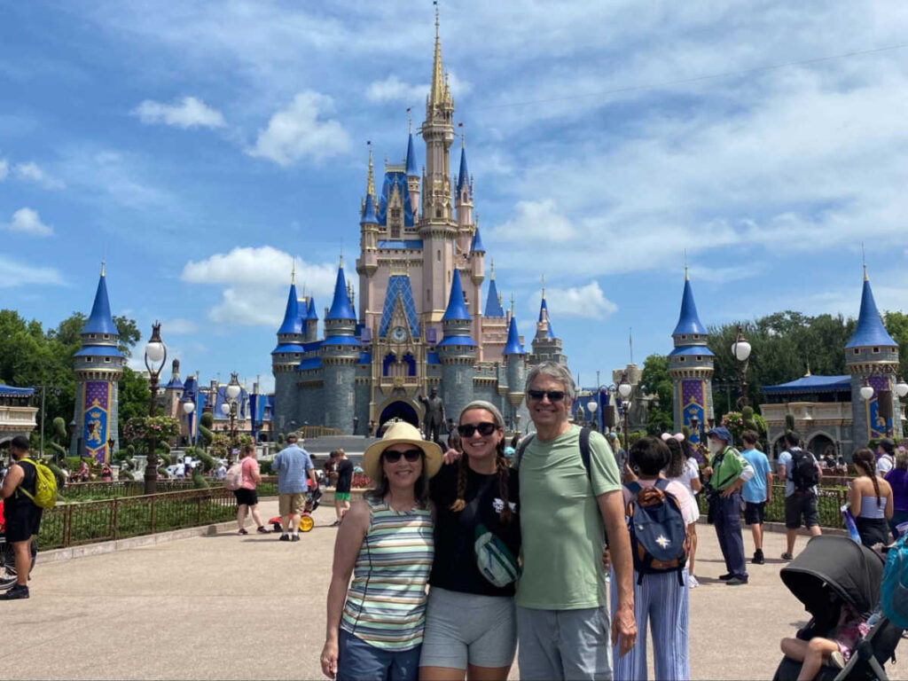 The author Laura McFarland and her parents posing for a photo in front of the castle in Disneyland