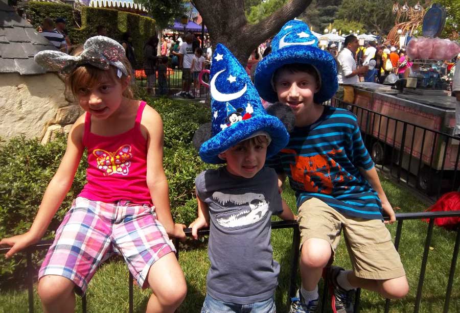 The author's kids smiling for a photo with their hats and Mickey Mouse ears