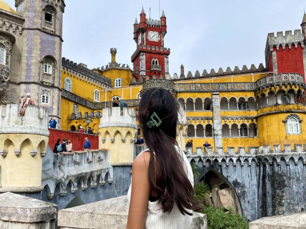Travel Lemming Editor Lea Rose Allbaugh, looking up at the vibrant exterior of National Palace of Pena in Portugal