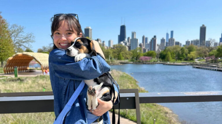 The author, Lea Rose Allbaugh with her dog smiling for a photo with the Chicago's skyscrapers on their background
