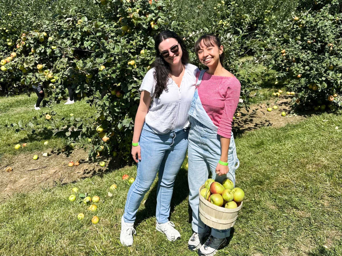 The author Lea Rose and her friend holding a basket of apples at Jeter Mountain Farm