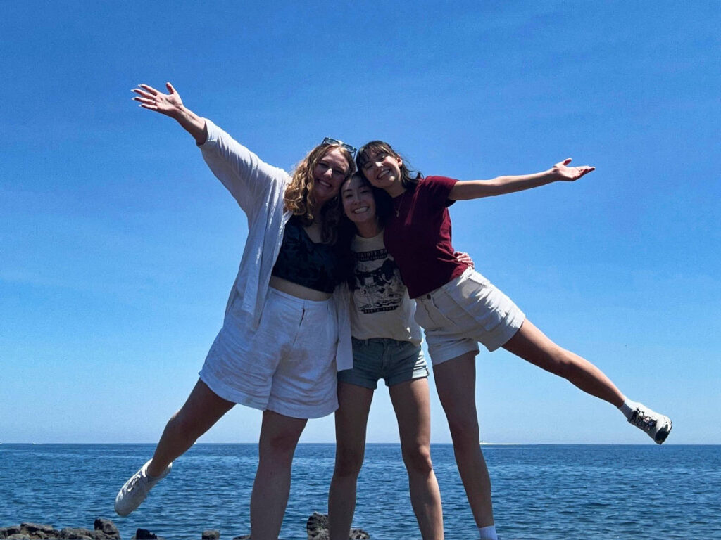 The author Lea Rose Allbaugh and her friends smiling for a photo in Aci Castello, Sicily