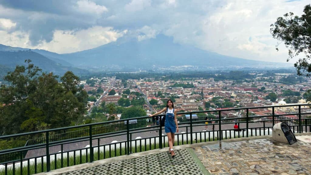 The author Lea Rose Allbaugh, posing with the Antigua cityscape and volcano from Cerro de La Cruz viewpoint