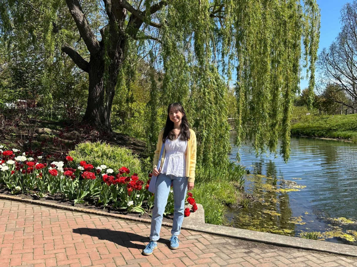 The author Lea Rose Allbaugh posing for a photo with the scenic view of the lake and blooming flowers around Chicago Botanic Garden
