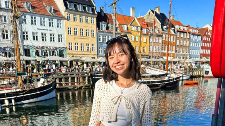 The author Lea Rose Allbaugh, posing for a photo in front of the colorful buildings in Copenhagen