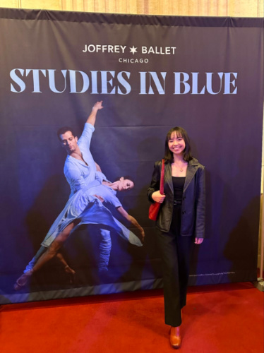 The author Lea Rose Allbaugh, posing for a photo in front of the Studies in Blue poster