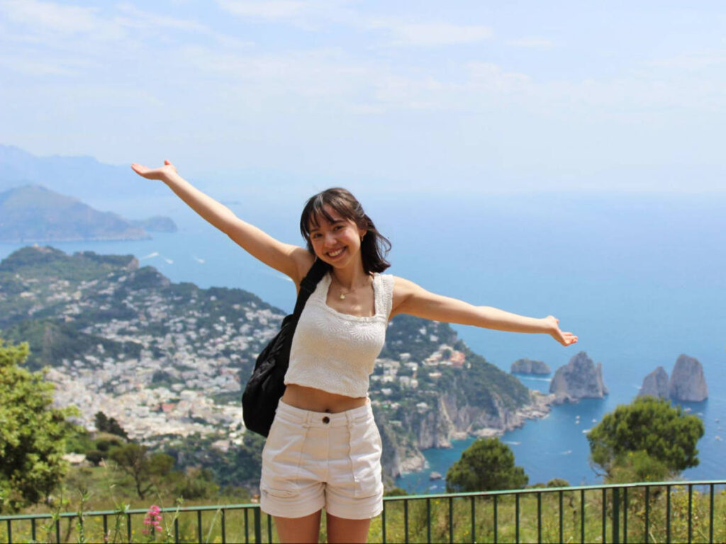 Travel Lemming Editor, Lea Rose, posing for a photo with an overlooking view in Capri