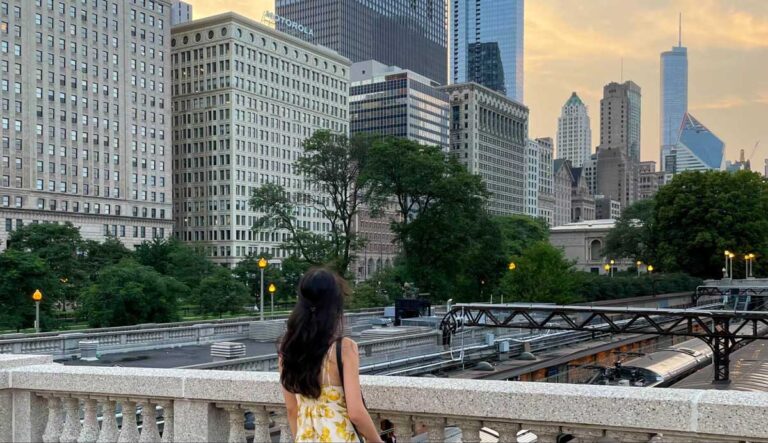 The author Lea Rose on a bridge overlooking Grant Park with Chicago's skyline of skyscrapers in the background