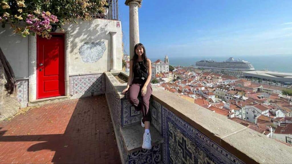 Lea Rose smiling for a photo with a view from Lisbon