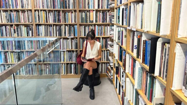 The author, Lea Rose reading a book at the Poetry Foundation