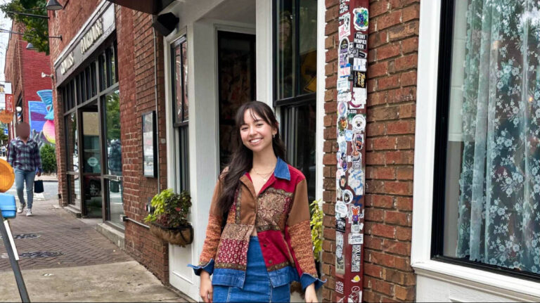 The author Lea Rose Allbaugh, posing for a photo in front of the stores in NoDa