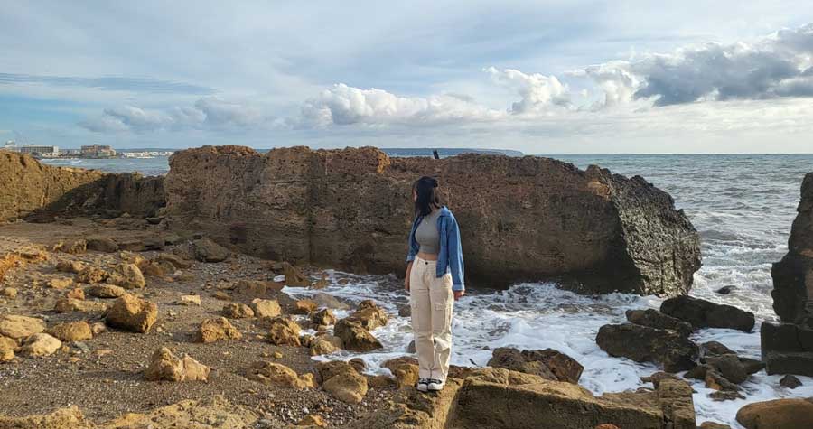 Lea Rose standing on a rock in a rocky seashore