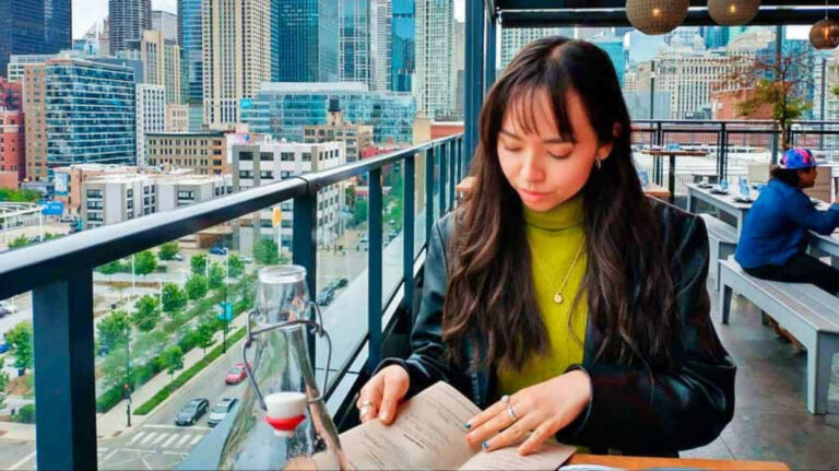 The author Lea Rose Allbaugh, dining at a rooftop patio overlooking Chicago cityscape