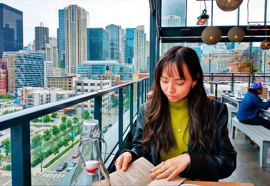 Travel Lemming Freelance Writer, Lea Rose, reading at a restaurant with magnificent Chicago views