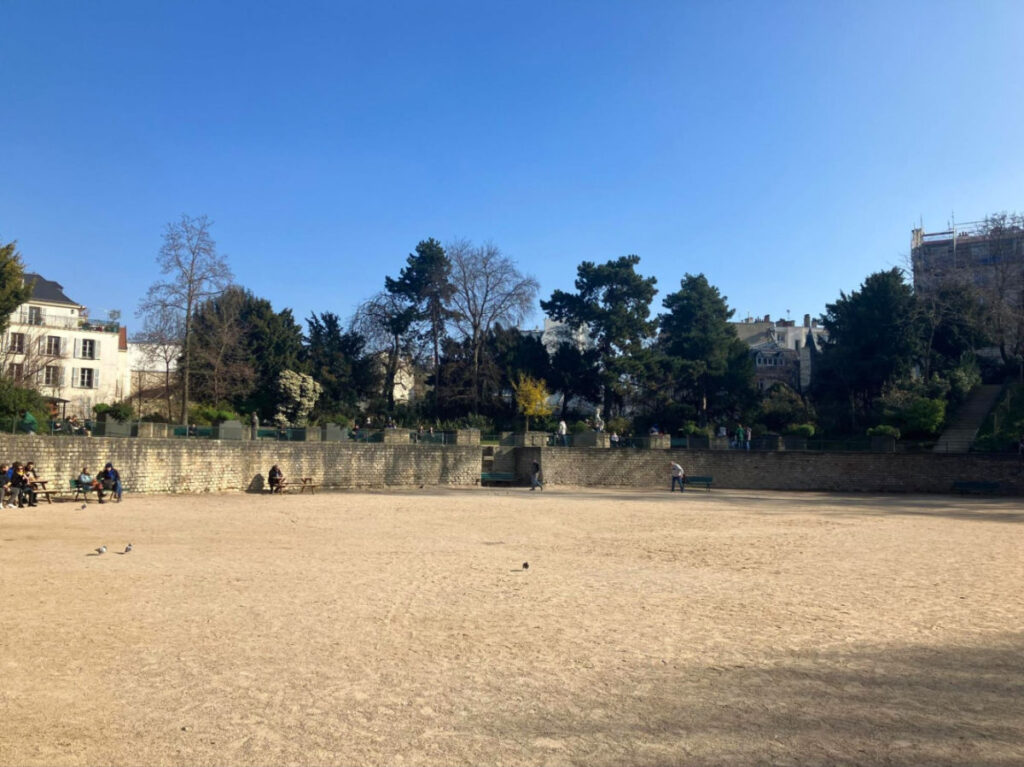 Open field and people sitting on the benches at Les Arènes de Lutèce in Saint-Victor