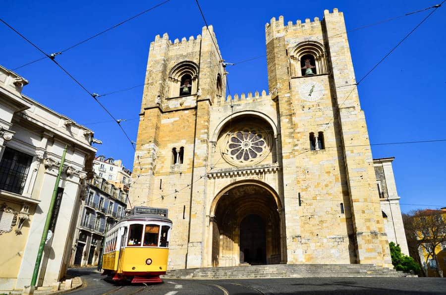 A yellow old tram passing the Se Cathedral in Lisbon
