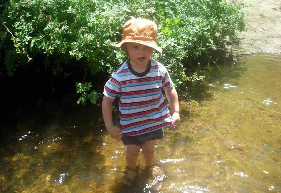 A little boy soaked in water during their hike