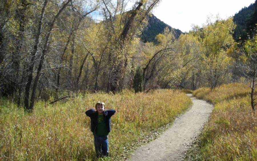 A little kid smiling for a photo during a hike with his family