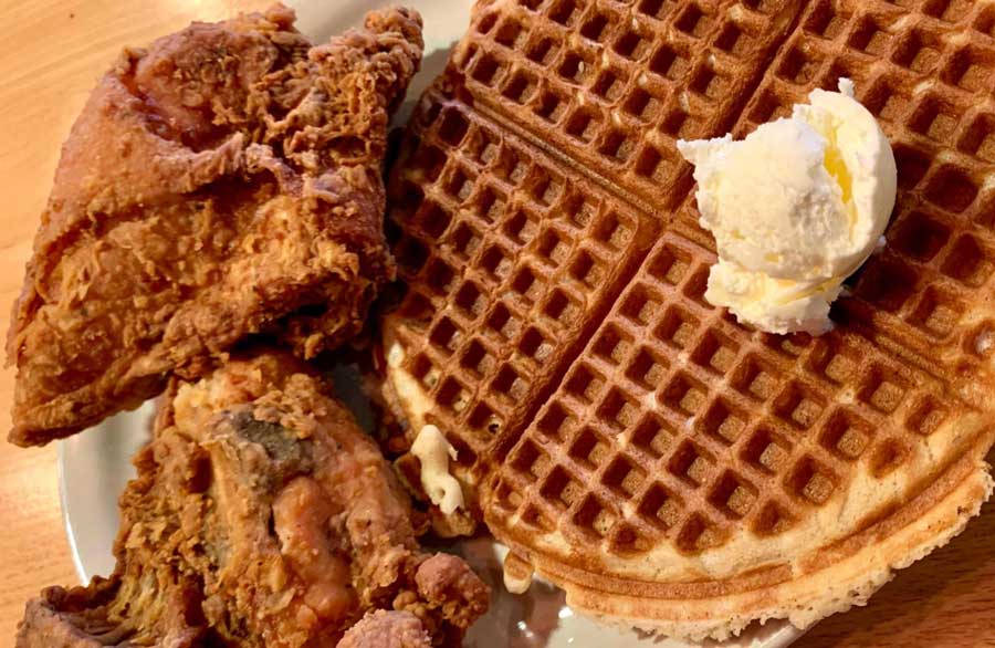 Two pieces of fried chicken and a waffle with a scoop of ice cream from Lolo's Chicken and Waffles