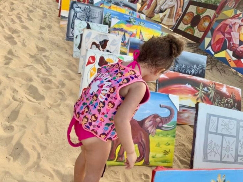 A kid looking at the local art on the beach in Punta Cana