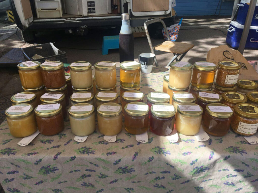 Various jars of local products displayed on a table at the Place des Lices market