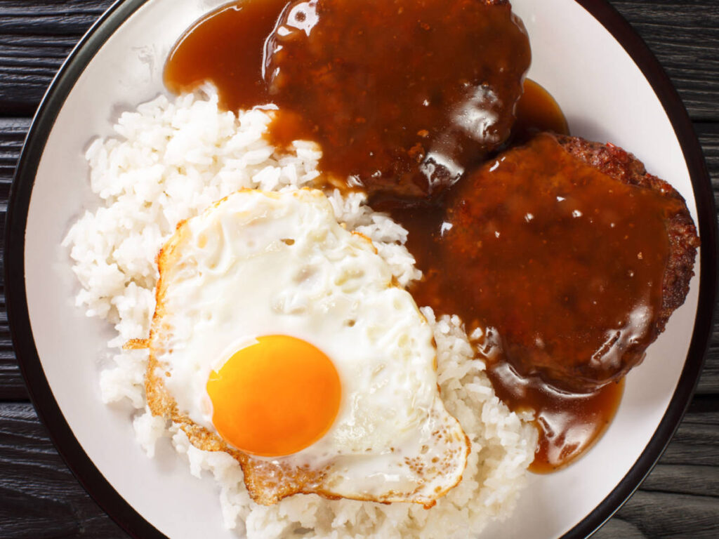 A plate of steamed rice with juicy hamburger steak, fried egg and gravy