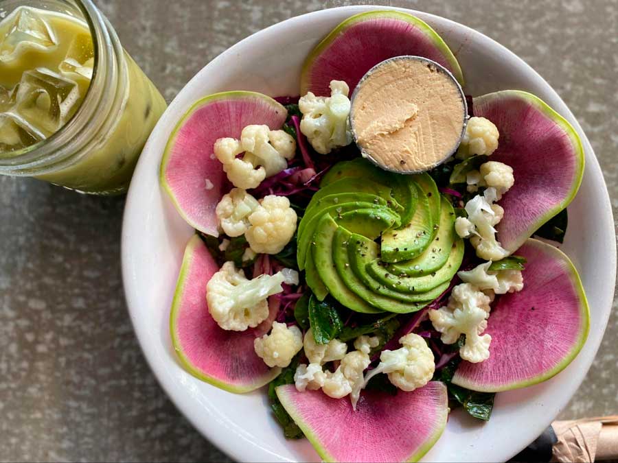 View of a fresh salad on a bowl and a glass of latte
