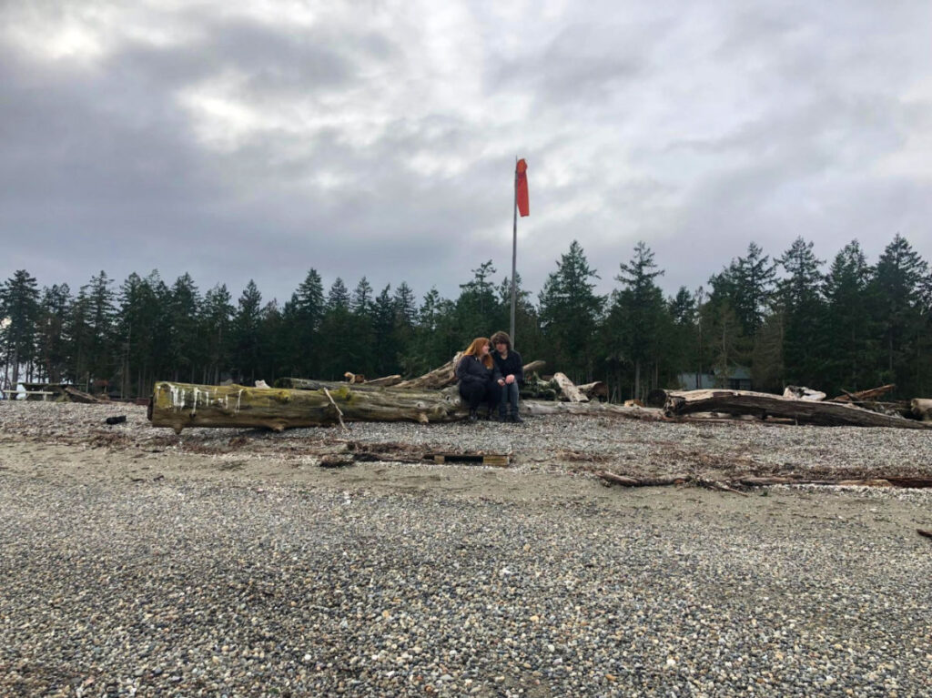 A couple sitting on a log at a campsite