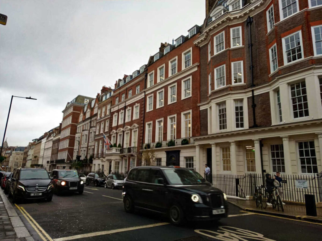 The taxis along the street with Victorian style buildings