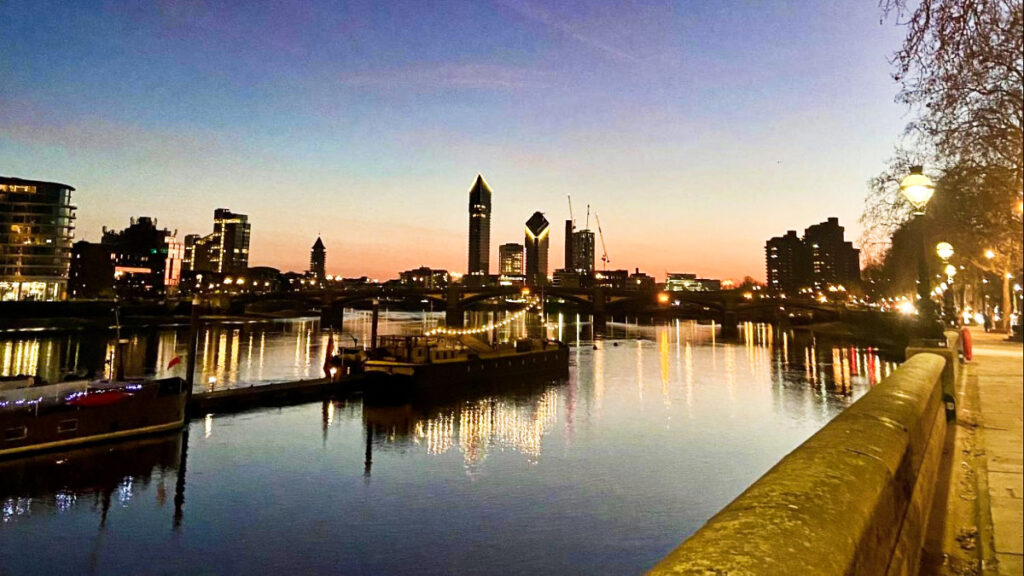 View of the illuminated buildings and docked boats in London at dusk
